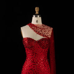 Close-up of a red crystal-embellished one-shoulder trumpet gown on a mannequin.