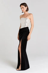 Side view of a strapless sequined bodice and velvet maxi skirt with a high slit