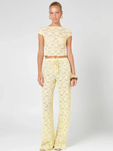 Sheer yellow lace cropped t-shirt and wide leg pants set on a model.