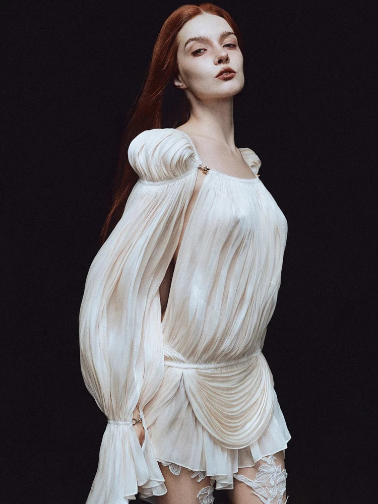Woman wearing a white, flowing dress against a black background