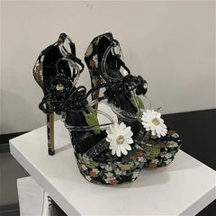 Black floral platform stiletto heels with lace-up ankle straps and flower embellishments.