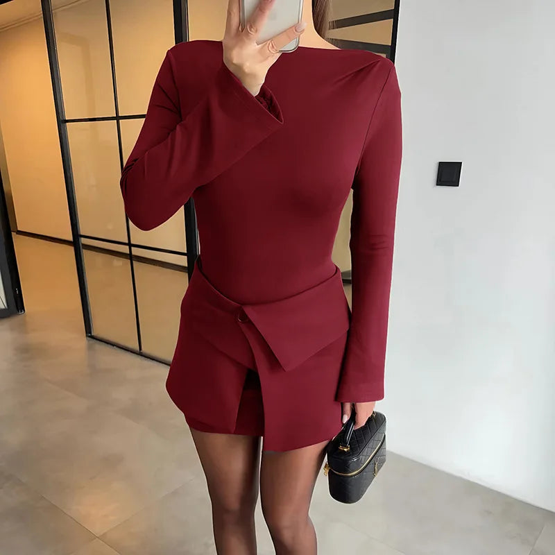 Person wearing a burgundy dress with long sleeves in an indoor setting.