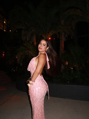 Woman in a pink dress standing outdoors at night with palm trees in the background
