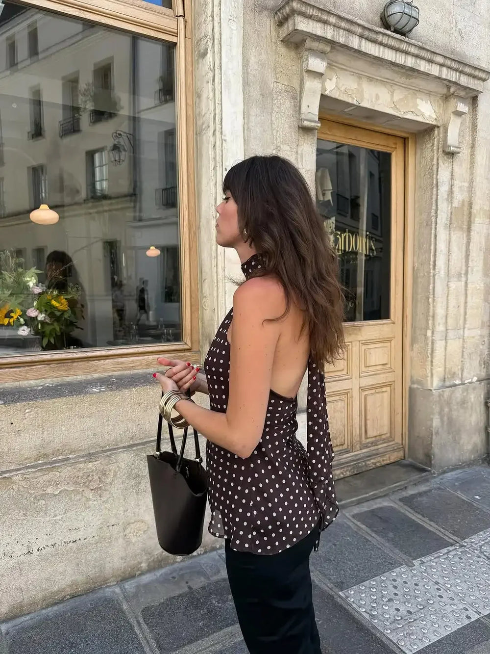 Woman standing on a street corner looking into a store window