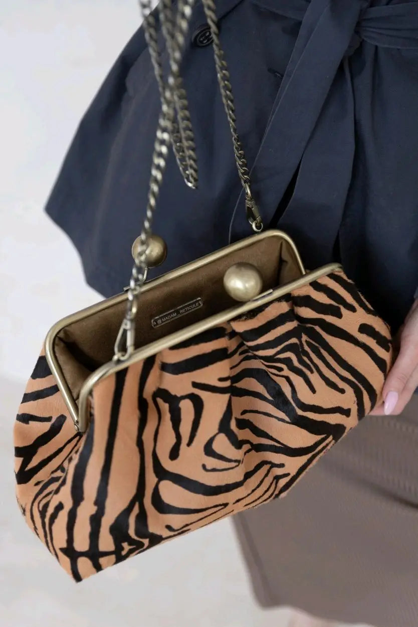 Zebra print handbag held by a person wearing a dark blue outfit.