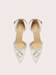 White high-heeled shoes with crystal embellishments on a light gray background