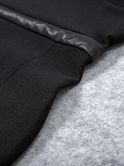 Close-up of a black jacket with leather trim on a gray surface