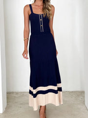 Woman wearing a navy blue dress with beige hem against a white background