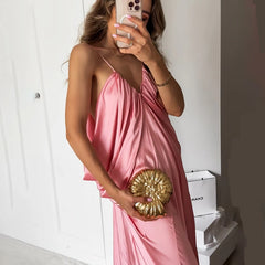 Woman in a pink dress holding a gold clutch in a minimalistic setting