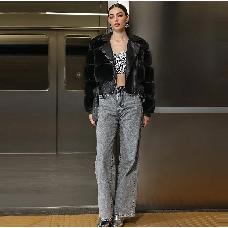 Person wearing a black leather jacket and gray jeans standing in a room with metallic walls.