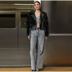 Person wearing a black leather jacket and gray jeans standing in a room with metallic walls.