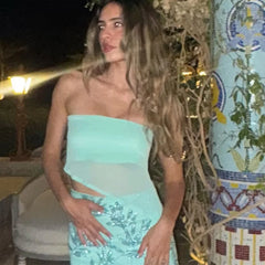 Woman in a light blue strapless top and sequined skirt standing outdoors at night.