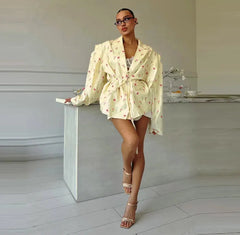 Woman in a light-colored floral outfit standing on a white pedestal in a minimalistic setting.