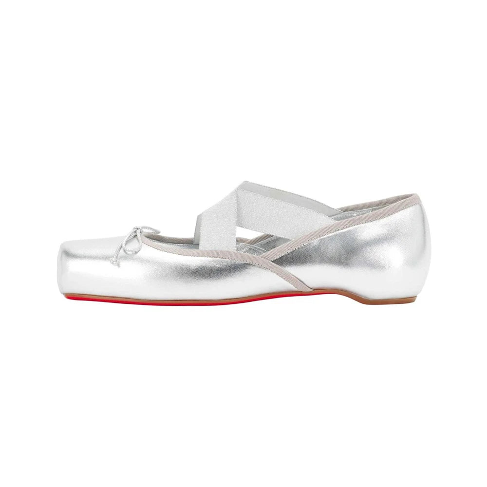 Silver ballet flats with a red sole on a white background