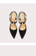 Pair of black high-heeled shoes with thin straps on a light gray background