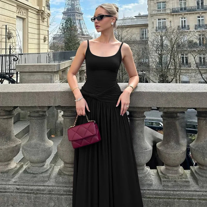 Woman in a black dress with a pink handbag standing on a balcony with the Eiffel Tower in the background