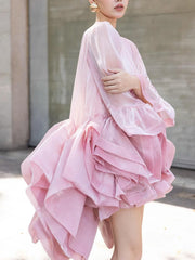 Side profile of a woman in a pink ruffled organza mini dress with bell sleeves.