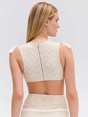 Woman wearing a beige lace top and skirt set on a plain background