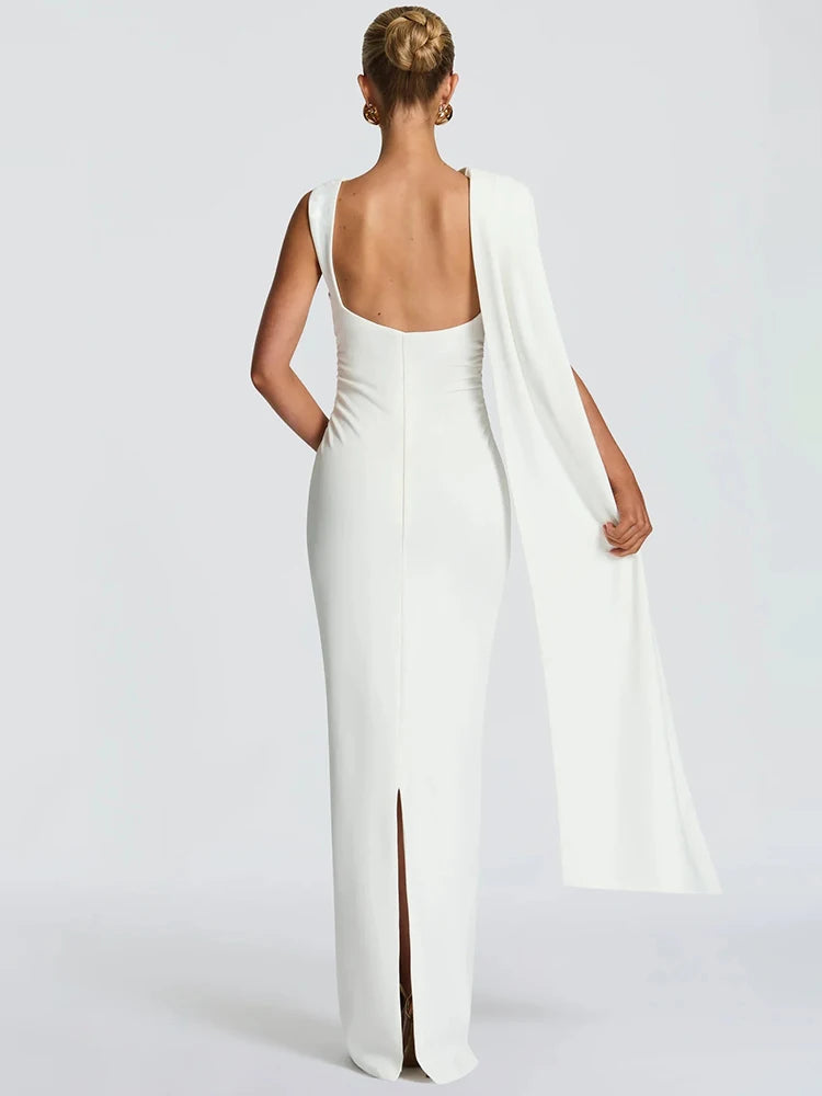 Woman wearing a white evening gown with a slit on a light gray background