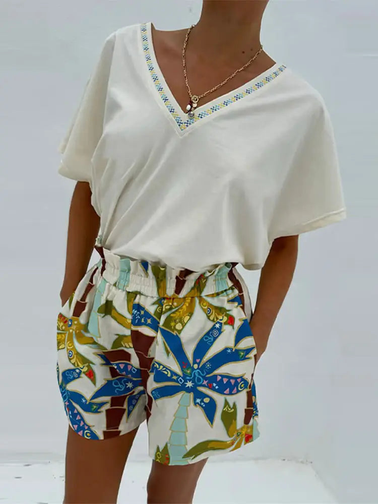 Person wearing a white top and colorful patterned shorts on a light gray background