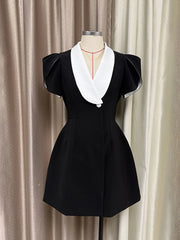 Black dress with white collar on a mannequin against a beige curtain background