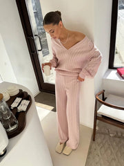 Woman in pink ribbed loungewear standing in a modern room.