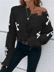 Person wearing a black sweater with white bone designs against a light gray wall.