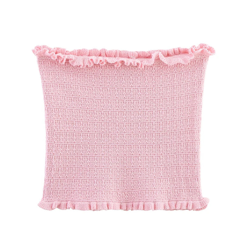 Pink textured pillow with ruffled edge on a white background