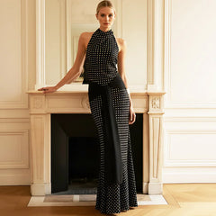 Woman wearing a black and white polka dot outfit standing in a room with a fireplace.