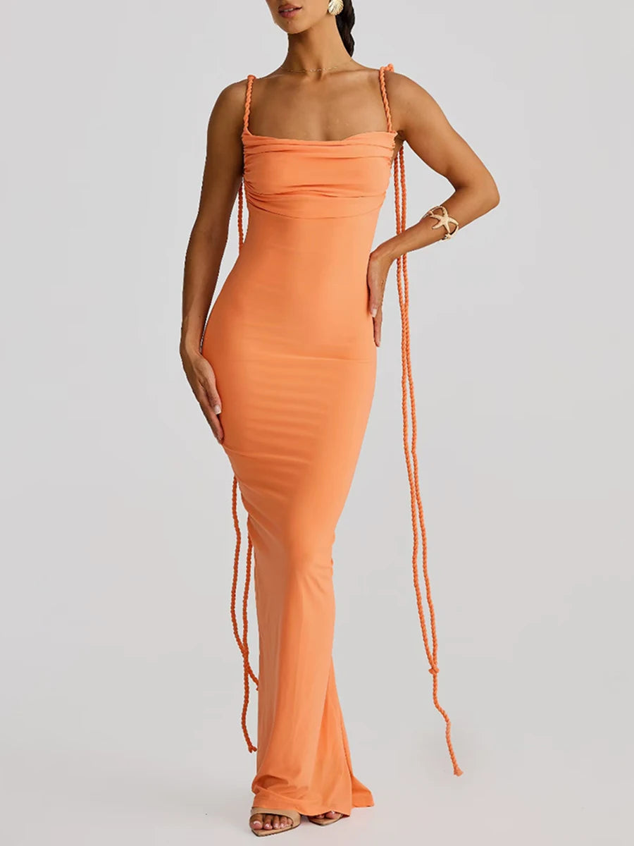 Woman wearing an orange dress with thin straps on a gray background