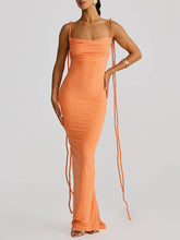 Woman wearing an orange dress with thin straps on a gray background