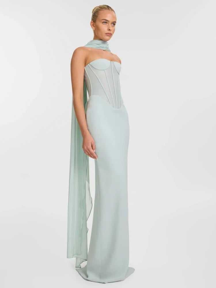 Woman wearing a light blue evening gown with a sheer overlay on a white background