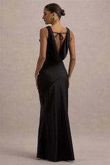 Woman wearing a black evening gown with a deep neckline against a beige background