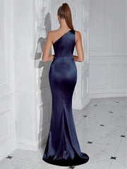 Woman wearing a one-shoulder navy blue evening gown in a white room.