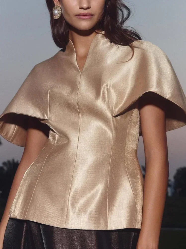 Woman wearing a gold satin top with a blurred background