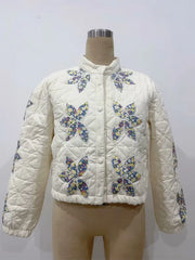 White quilted jacket with butterfly patterns on a mannequin against a white background