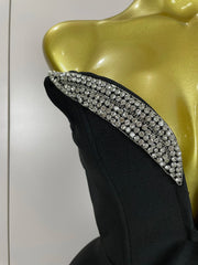 Black evening gown with a large bow and crystal embellishments on a mannequin.