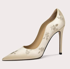 Beige high-heeled shoe with floral embroidery on a light gray background