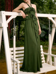 Woman in a green dress sitting on a white swing with a blurred natural background