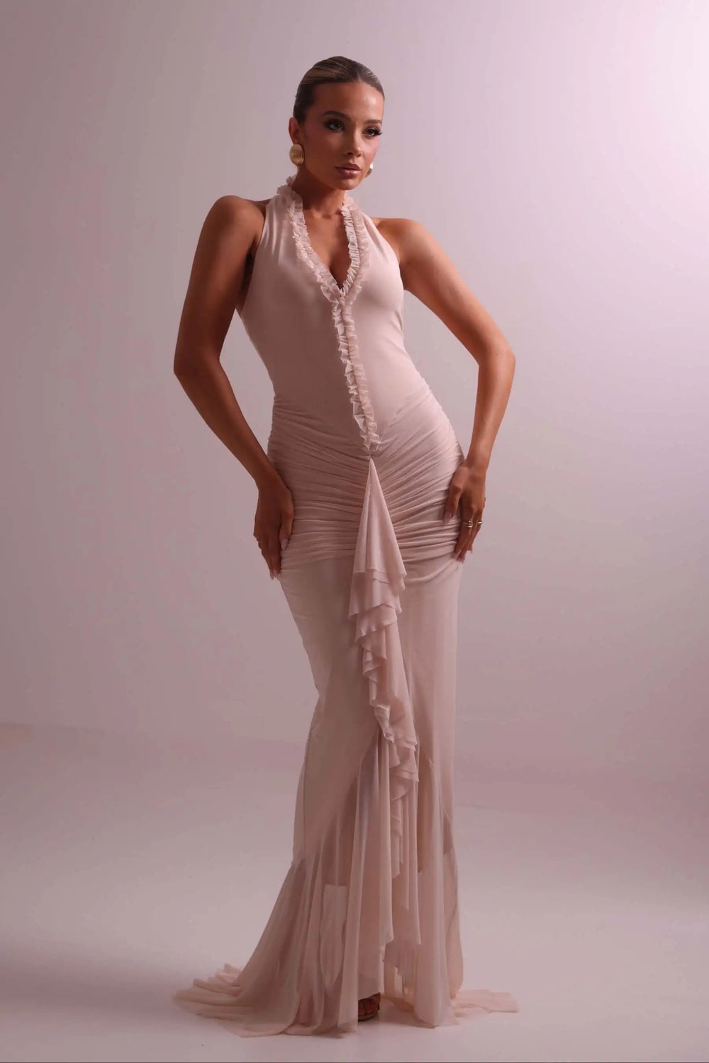 Woman wearing a beige evening gown against a plain background