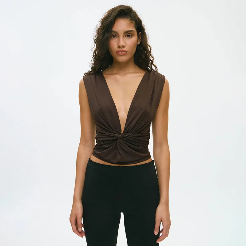 Woman wearing a brown top with a deep neckline and black pants on a white background
