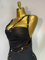 Black dress with gold accents on a mannequin against a white background