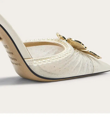 White high-heeled shoe with decorative elements on a light gray background