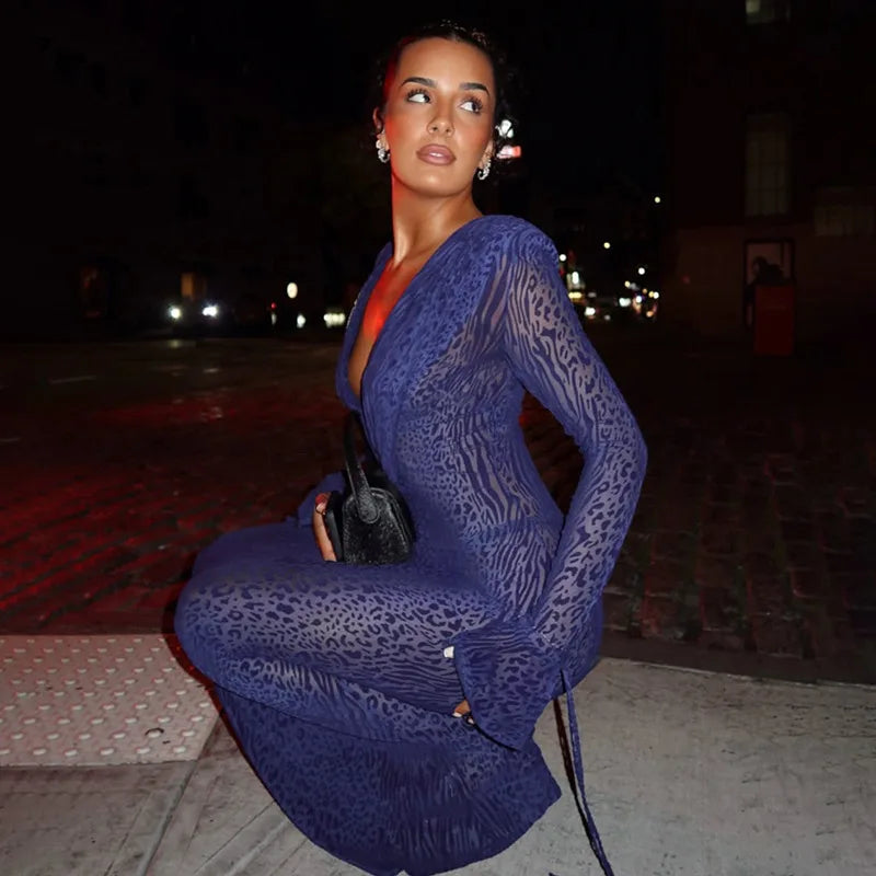 Woman in a blue lace dress sitting on a curb at night.