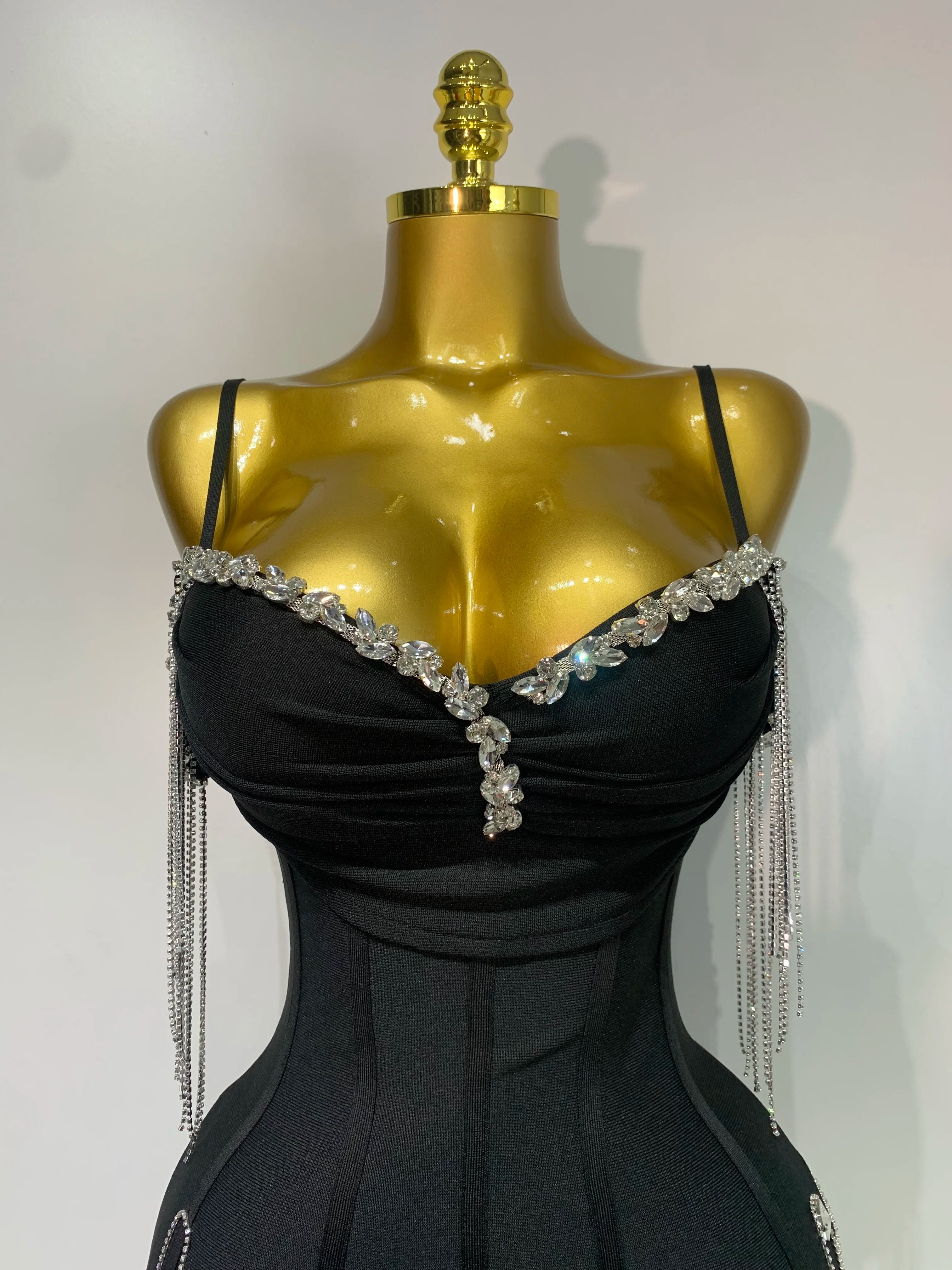 Black evening gown with crystal embellishments on a gold mannequin against a white background