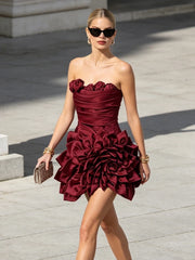Model wearing a burgundy strapless 3D rose mini dress outdoors