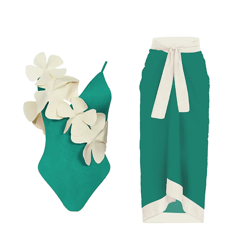 Teal one-piece swimsuit with white floral embellishment and a teal wrap skirt with white trim.