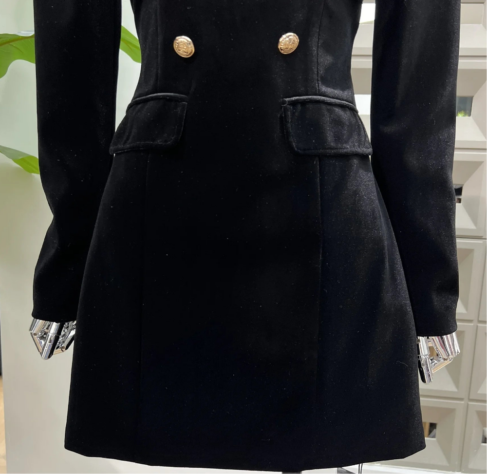 Black mini dress with gold buttons on a mannequin in an indoor setting