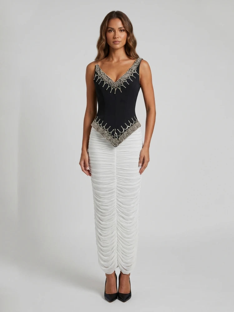 Full length view of a black beaded V-neck sleeveless top paired with a white ruched floor-length skirt.