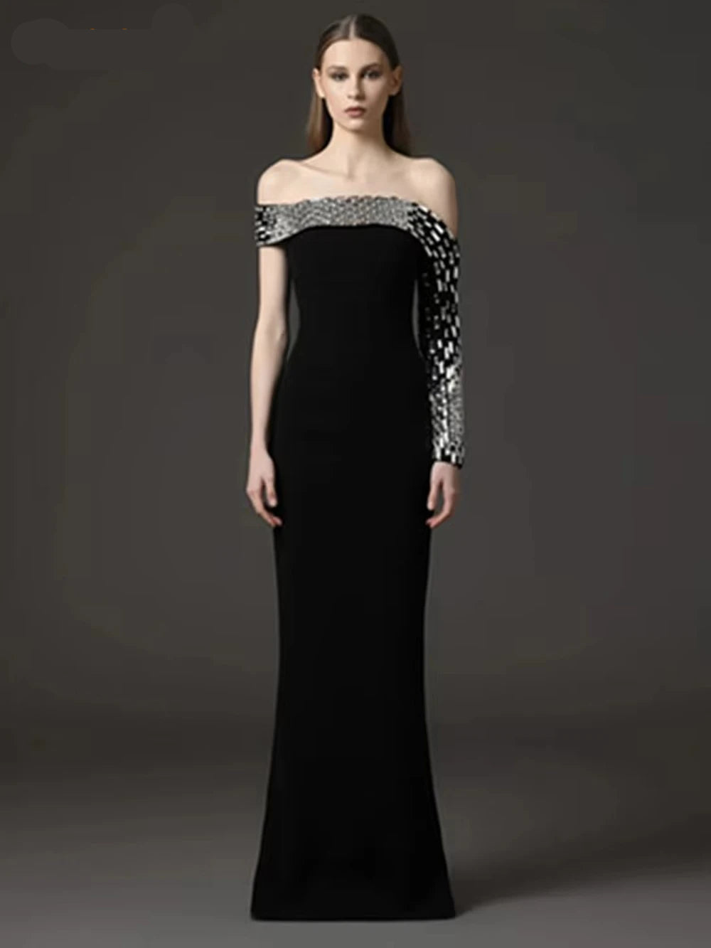 Woman wearing a black off-shoulder evening gown with silver embellishments on a dark background, branded 'Modphy'.